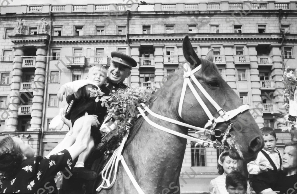 Герой Советского Союза генерал-майор А.Ф. Щеглов сажает на своего коня мальчика, подарившего ему букет цветов. 8 июля 1945г. Ленинград. Автор съемки: Чертов Г.И. ЦГАКФФД СПб. 