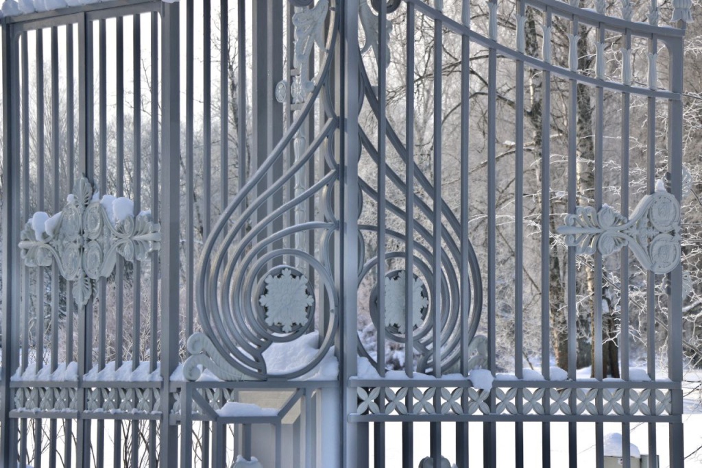 Изящные кованые ворота опирались на пилоны чугунного литья и были увенчаны декоративными вазами с фруктами. 
